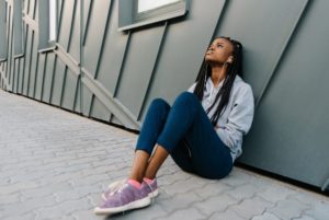 Girl stressed out, sitting along a wall